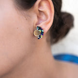 Close-up of a woman’s ear wearing colorful, crescent-shaped Minimalist Geometric Stud Earrings with a round gold stud. The womans dark hair is tied back in a bun. These hypoallergenic earrings are lightweight and set against a softly blurred background.